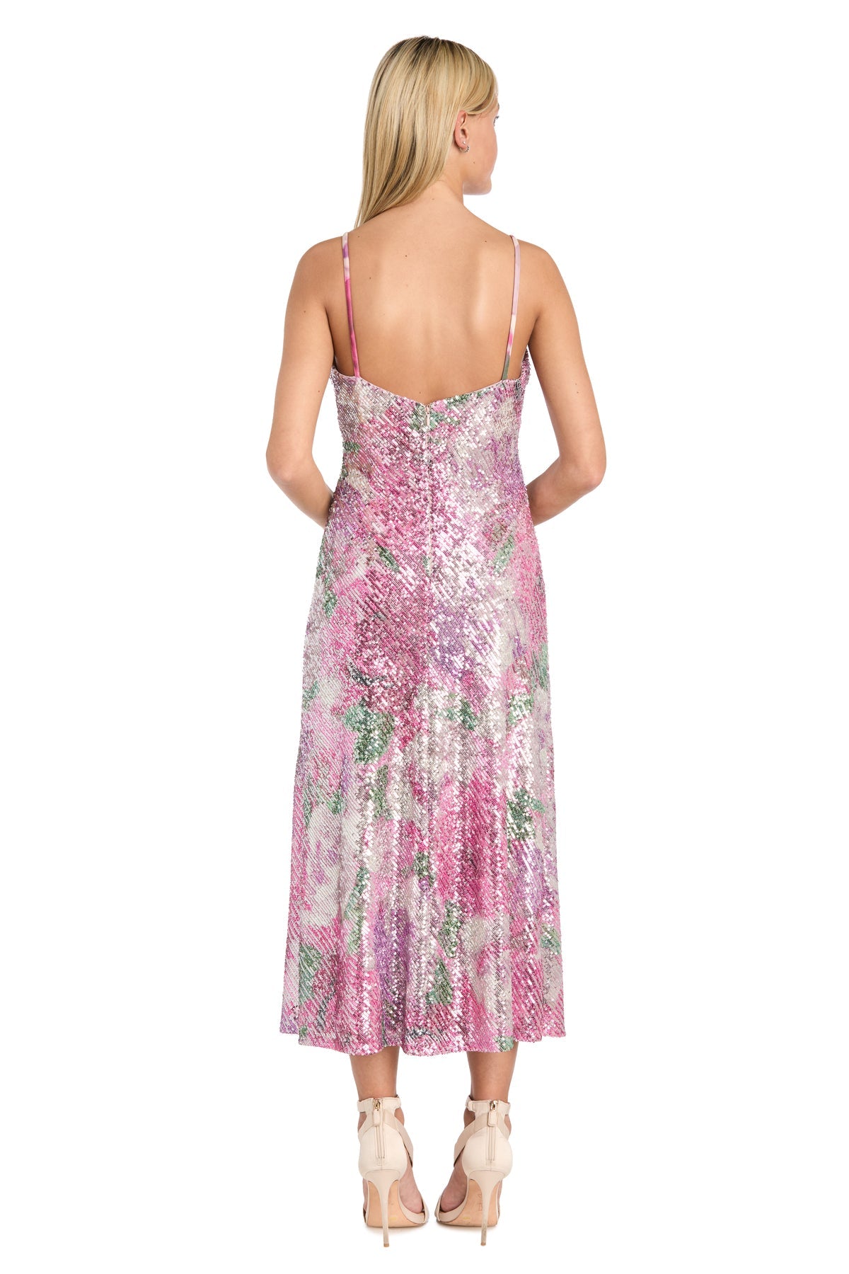 A woman facing away, wearing the Semi-Formal Floral Sequin Dress: Morgan 10253 with thin straps and beige heels, stands against a white background.